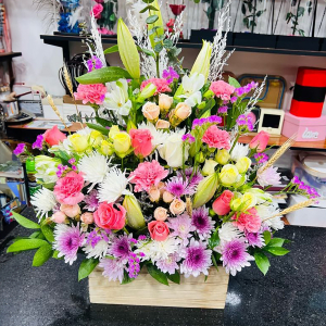  - Arrangement of of mixed colourful flowers in a box with foliage